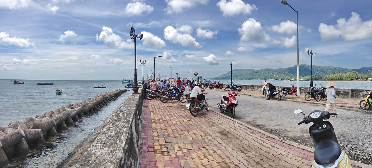 Lối ra cầu tàu, xe máy và thuyền trên mặt biển phía xa.