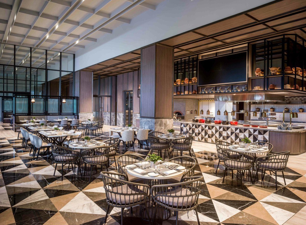 Phòng ăn trần cao, sàn gạch hoa văn tam giác, bàn ghế mây và quầy buffet