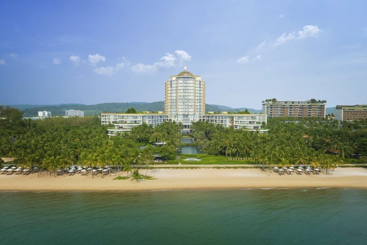 Khu nghỉ dưỡng InterContinental Phú Quốc nhìn từ biển, bãi cát vàng phía trước, tòa tháp cao ở giữa hàng dừa