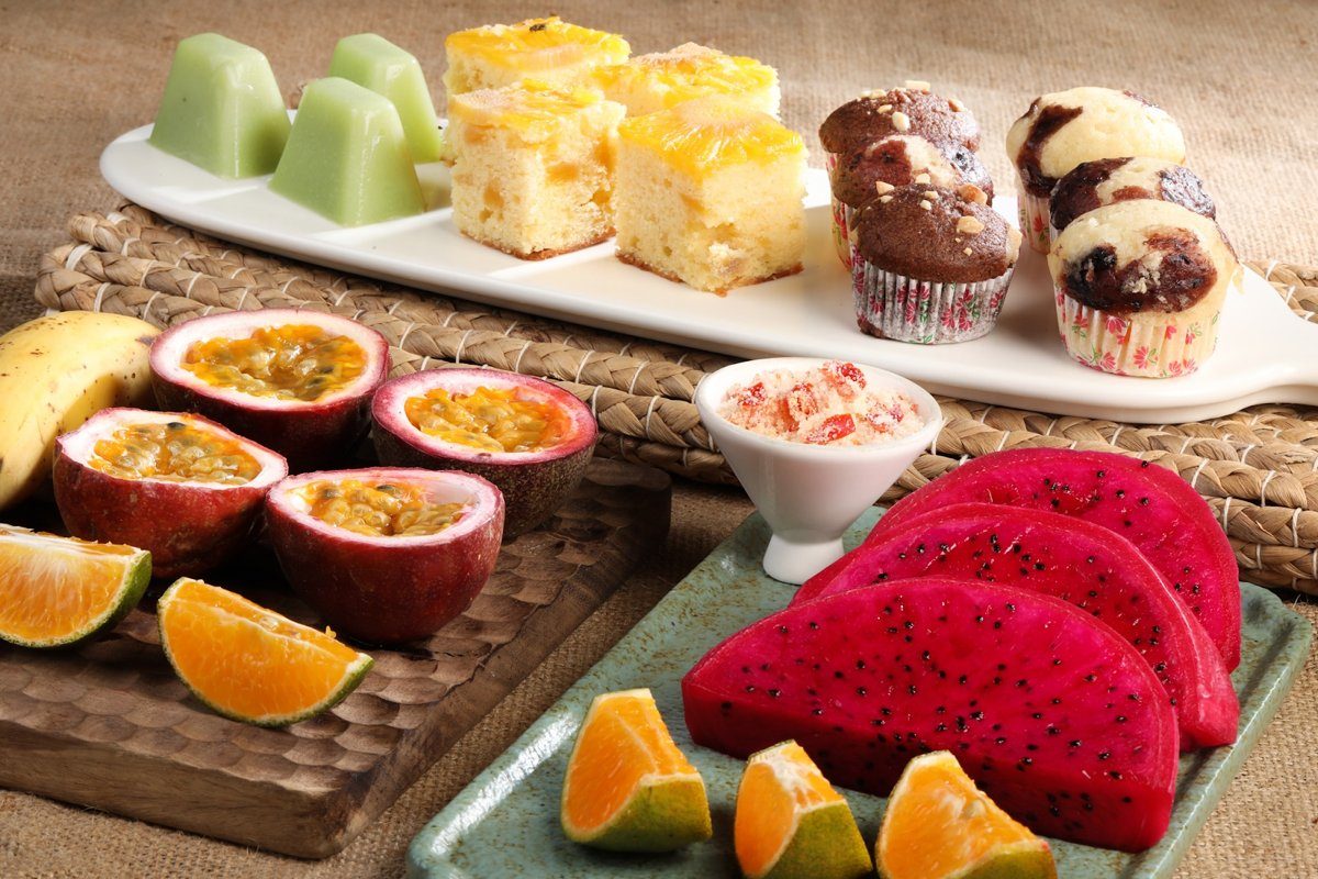 Khay bánh bông lan, bánh muffin, rau câu xanh cùng thanh long đỏ, chanh dây và cam cắt lát