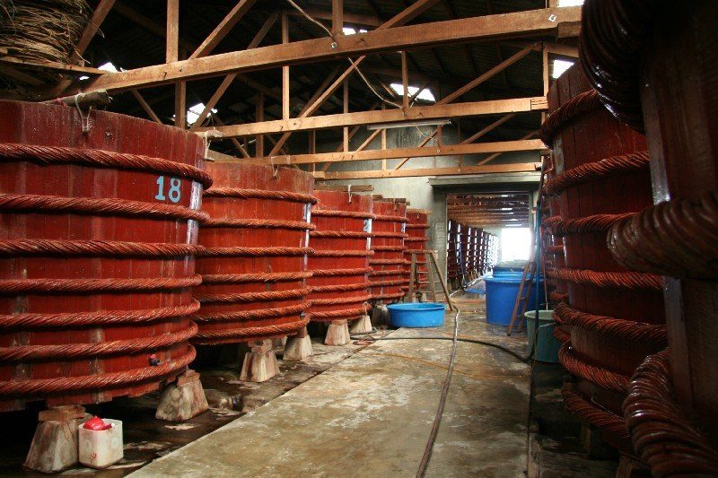Các thùng gỗ ủ nước mắm có đánh số, xếp thành dãy dưới mái nhà xưởng.