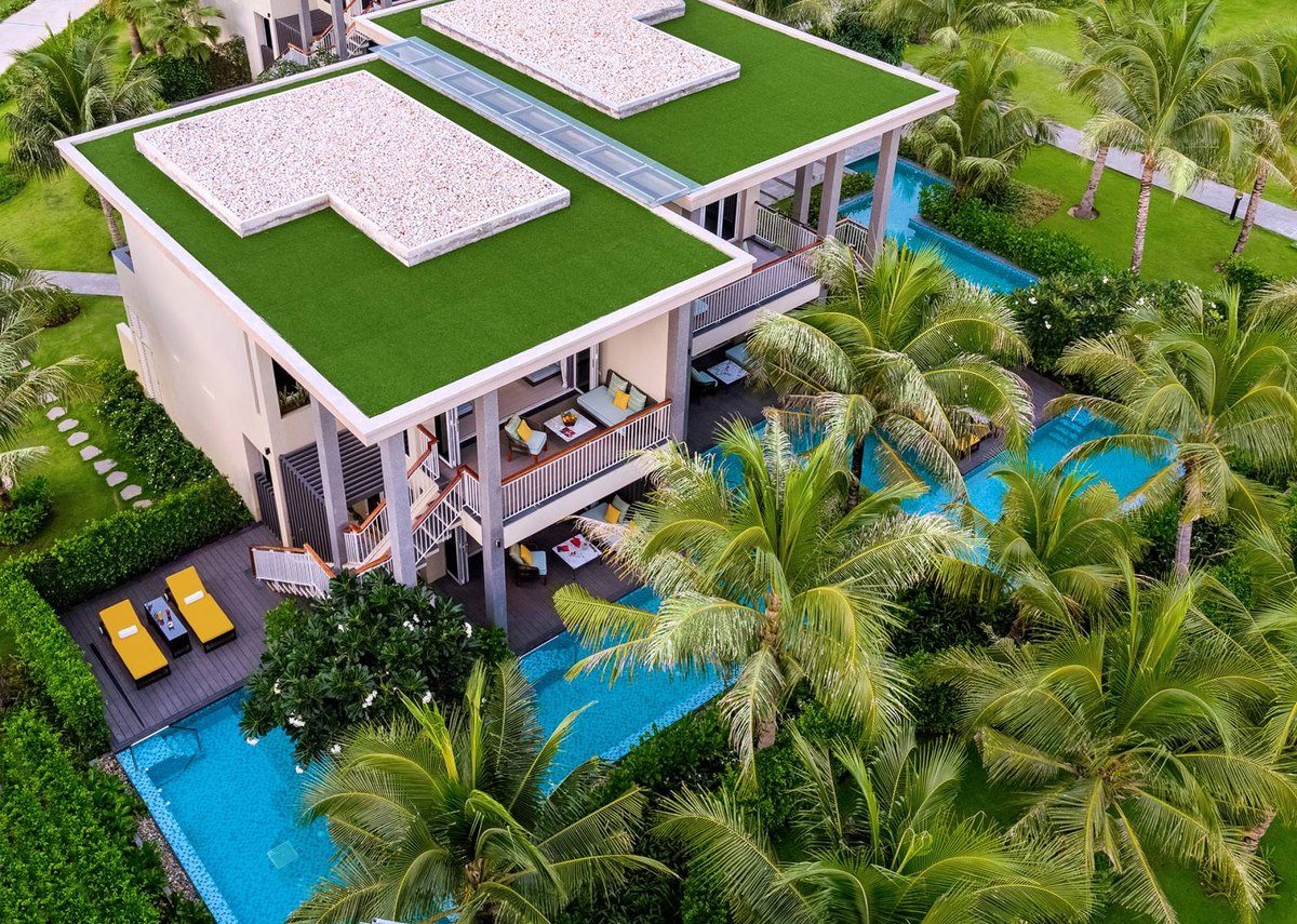 Nhìn từ trên cao xuống một căn cabana hai tầng mái cỏ, có hồ bơi và ghế tắm nắng trước hiên